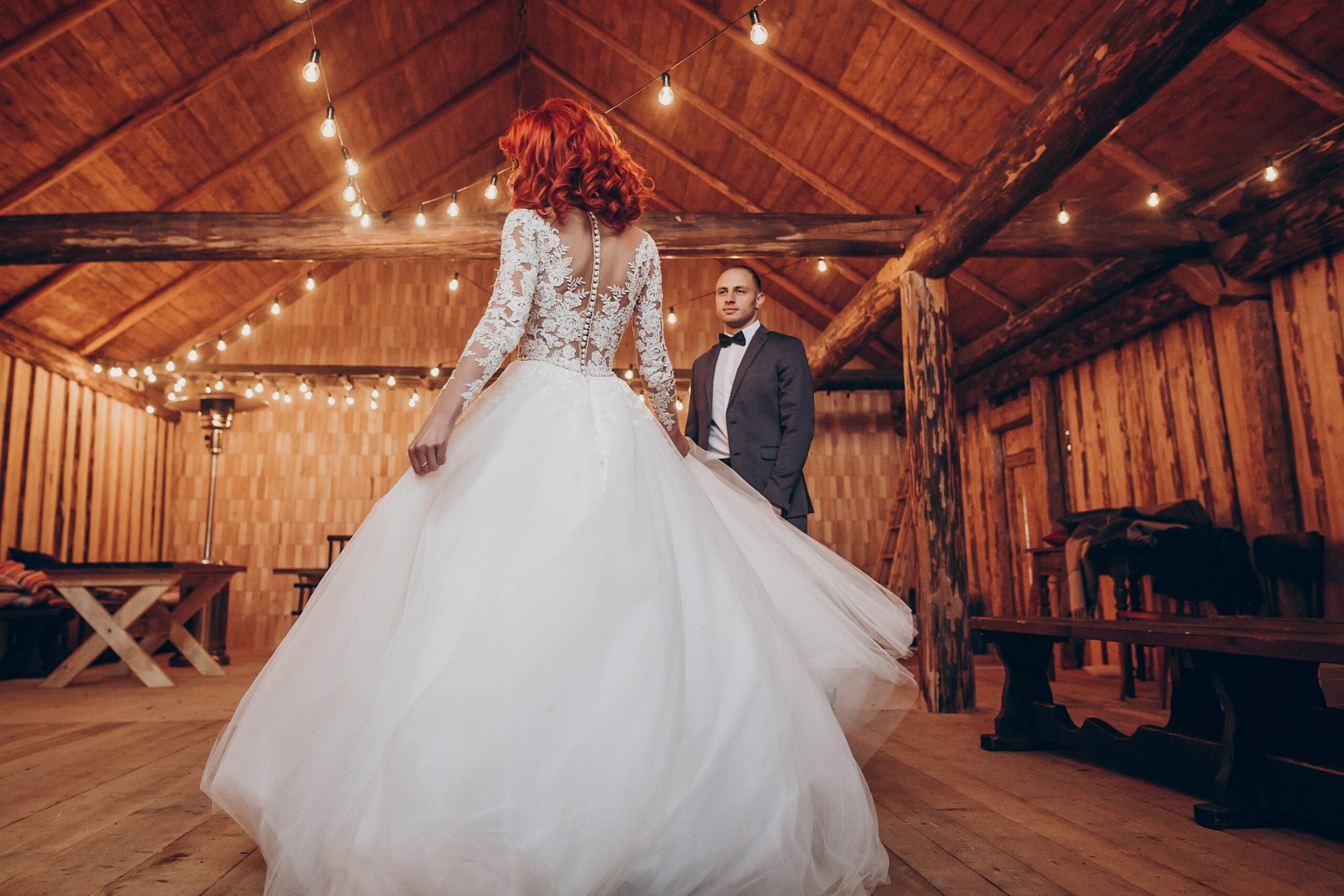 rustic wedding couple dancing under retro bulbs lights in wooden